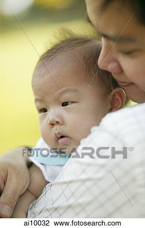 Stock Image - Father carrying baby, over the shoulder view.. Fotosearch