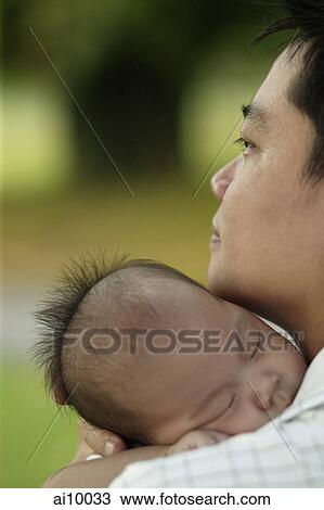 Stock Image - Father carrying sleeping baby, over the shoulder view.. Fotosearch