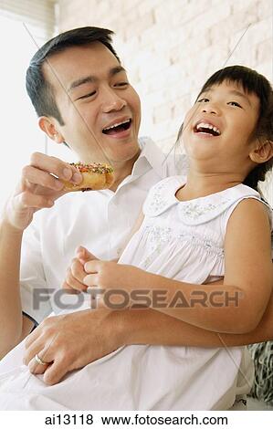Father feeding daughter a donut View Large Photo Image Stock Photo - Father feeding daughter a donut. Fotosearch