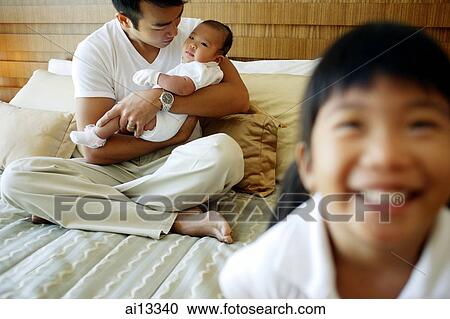 Father holding baby, older child in foreground View Large Photo Image Stock Image - Father holding baby, older child in foreground. Fotosearch