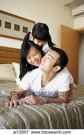 Father, mother and daughter lying on bed, on top of one another View Large Photo Image Stock Photo - Father, mother and daughter lying on bed, on top of one another. Fotosearch