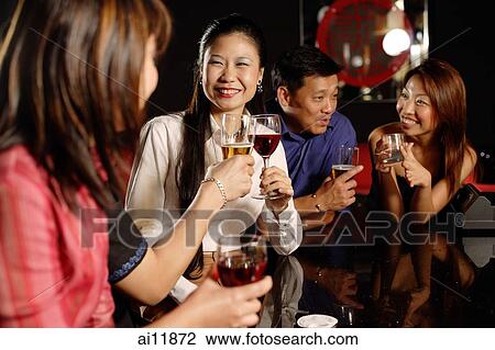 Friends at a bar, holding drinks View Large Photo Image Stock Image - Friends at a bar, holding drinks. Fotosearch
