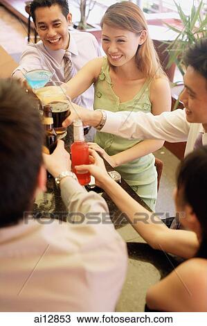 Friends at bar counter raising drinks for a toast, high angle view View Large Photo Image Stock Image - Friends at bar counter raising drinks for a toast, high angle view. Fotosearch
