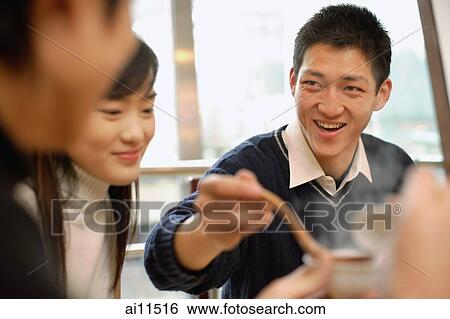 Friends eating at restaurant, man holding soup ladle View Large Photo Image Stock Photograph - Friends eating at restaurant, man holding soup ladle. Fotosearch