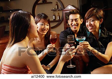 Stock Image - Friends in entertainment club, toasting with drinks. Fotosearch