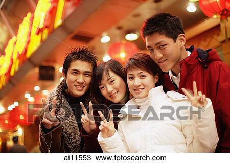 Friends looking at camera, smiling, making peace signs View Large Photo Image Stock Image - Friends looking at camera, smiling, making peace signs. Fotosearch