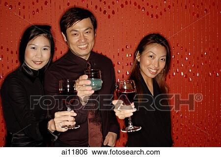 Friends raising wine glasses, looking at camera View Large Photo Image Stock Photograph - Friends raising wine glasses, looking at camera. Fotosearch