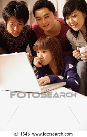 Stock Photography - Friends sitting around laptop. Fotosearch