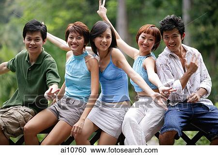 Stock Image - Friends sitting side by side, posing. Fotosearch