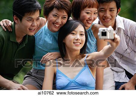 Friends sitting side by side, posing for camera View Large Photo Image Stock Image - Friends sitting side by side, posing for camera. Fotosearch