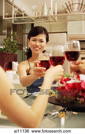 Friends toasting wine glasses across dinner table View Large Photo Image Stock Photograph - Friends toasting wine glasses across dinner table. Fotosearch