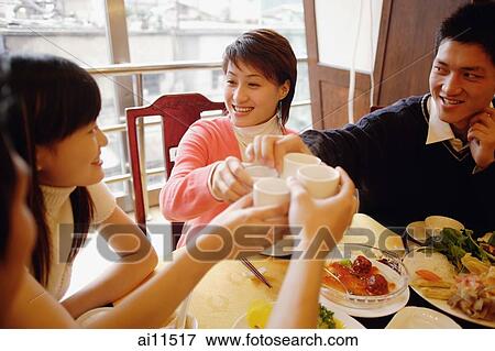Stock Photo - Friends toasting with tea at restaurant. Fotosearch