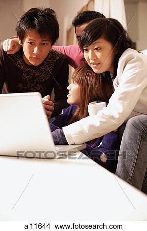 Picture - Friends using computer at home. Fotosearch