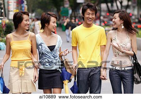 Friends walking side by side, talking, carrying bags View Large Photo Image Stock Photo - Friends walking side by side, talking, carrying bags. Fotosearch