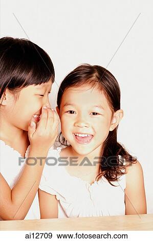 Girl whispering in young girl's ear View Large Photo Image Stock Photo - Girl whispering in young girl's ear. Fotosearch