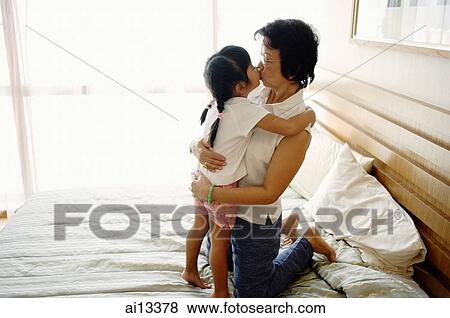 Granddaughter kissing grandmother on bed View Large Photo Image Stock Photo - Granddaughter kissing grandmother on bed. Fotosearch