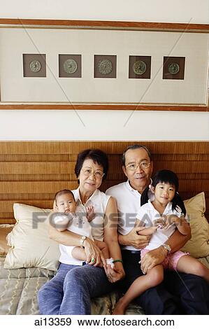 Grandparents with grandchildren, sitting on bed, looking at camera View Large Photo Image Stock Photo - Grandparents with grandchildren, sitting on bed, looking at camera. Fotosearch