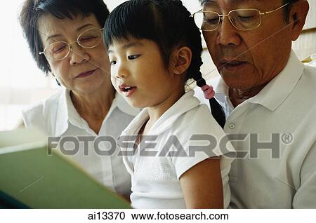 Grandparents with granddaughter, reading a book View Large Photo Image Stock Image - Grandparents with granddaughter, reading a book. Fotosearch