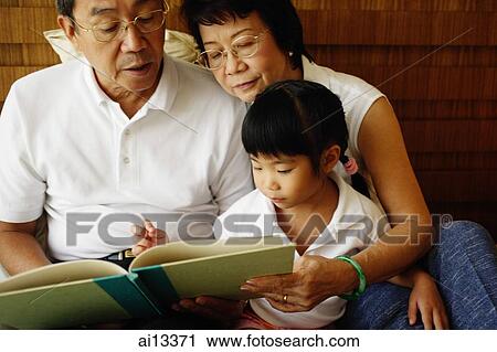 Grandparents with granddaughter, reading a book View Large Photo Image Stock Image - Grandparents with granddaughter, reading a book. Fotosearch