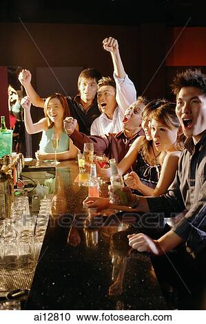 Group of friends sitting at bar, arms raised View Large Photo Image Stock Image - Group of friends sitting at bar, arms raised. Fotosearch