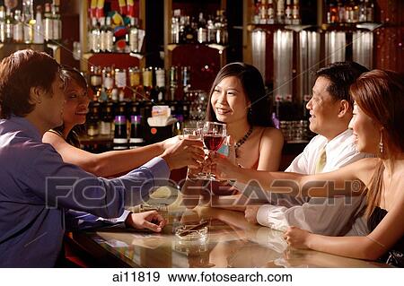 Group of people sitting around table toasting View Large Photo Image Stock Photo - Group of people sitting around table toasting. Fotosearch
