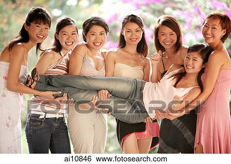 Stock Photograph - Group of young women, posing for camera, carrying one girl between them. Fotosearch