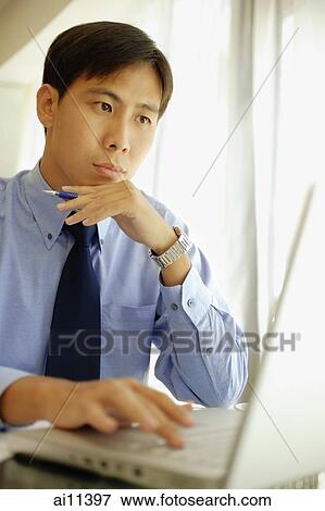 Male executive using laptop, hand on chin View Large Photo Image Stock Photo - Male executive using laptop, hand on chin. Fotosearch