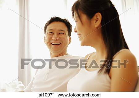 Stock Image - Man and a woman sitting down side by side, talking. Fotosearch