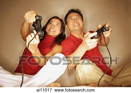 Stock Photo - Man and woman playing with handheld video game. Fotosearch
