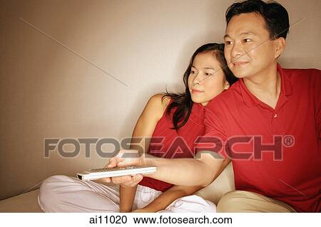 Man and woman sitting side by side, man with remote control View Large Photo Image Stock Image - Man and woman sitting side by side, man with remote control. Fotosearch