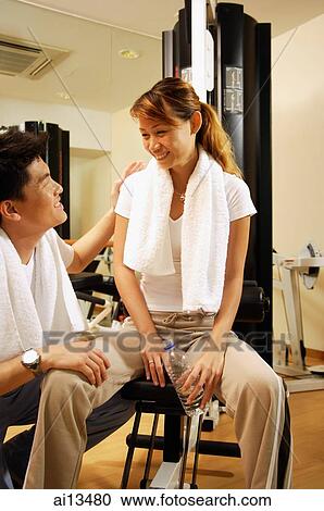 Man crouching down, woman sitting on exercise machine View Large Photo Image Stock Image - Man crouching down, woman sitting on exercise machine. Fotosearch