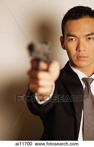 Man dressed in suit, holding gun View Large Photo Image Stock Image - Man dressed in suit, holding gun. Fotosearch