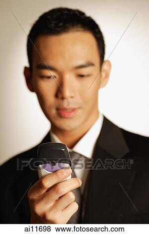 Man dressed in suit, looking at mobile phone View Large Photo Image Stock Photo - Man dressed in suit, looking at mobile phone. Fotosearch