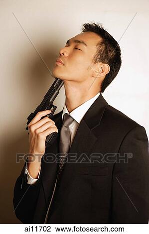Man dressed in suit, pointing gun at chin View Large Photo Image Stock Image - Man dressed in suit, pointing gun at chin. Fotosearch