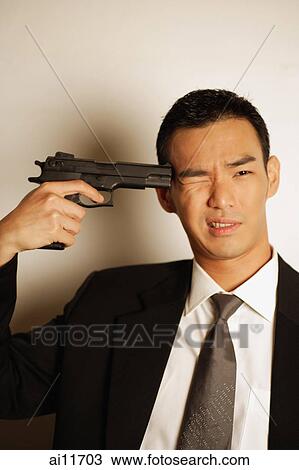 Man dressed in suit, pointing gun at head, one eye closed View Large Photo Image Stock Image - Man dressed in suit, pointing gun at head, one eye closed. Fotosearch