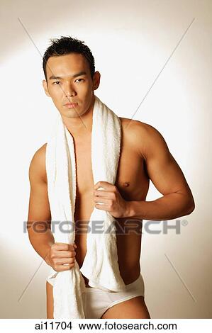 Man dressed in trunks, holding towel slung over his neck View Large Photo Image Picture - Man dressed in trunks, holding towel slung over his neck. Fotosearch