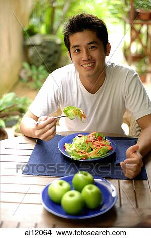 Man eating salad, looking at camera View Large Photo Image Picture - Man eating salad, looking at camera. Fotosearch