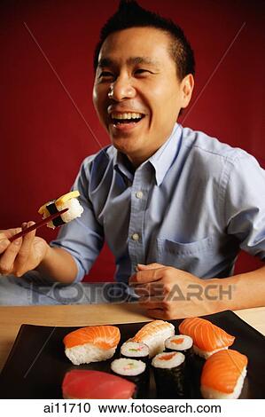 Man eating sushi with chopsticks View Large Photo Image Stock Image - Man eating sushi with chopsticks. Fotosearch