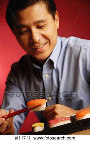 Man eating sushi with chopsticks View Large Photo Image Stock Image - Man eating sushi with chopsticks. Fotosearch