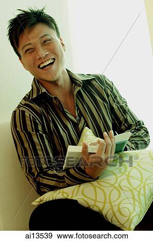 Stock Photo - Man holding a book, looking at camera, smiling. Fotosearch