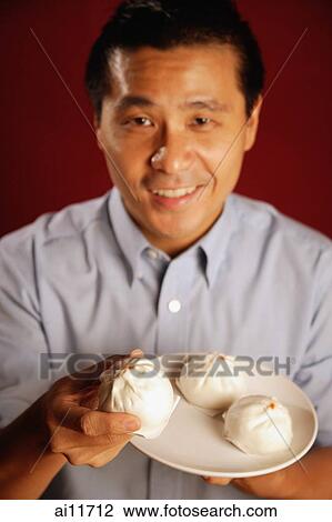 Man holding a plate of buns View Large Photo Image Stock Image - Man holding a plate of buns. Fotosearch
