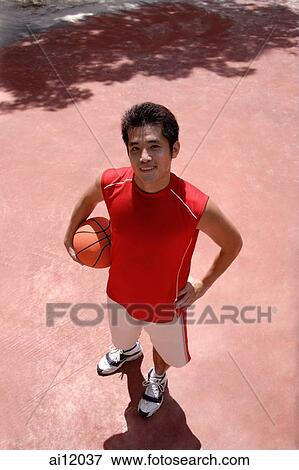 Stock Photo - Man holding basketball, looking at camera. Fotosearch
