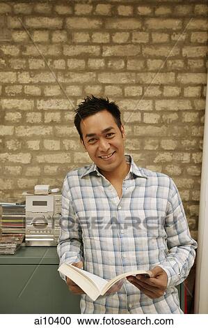 Stock Image - Man holding book, looking at camera. Fotosearch