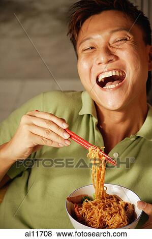 Man holding bowl of noodles and chopsticks, laughing View Large Photo Image Stock Photo - Man holding bowl of noodles and chopsticks, laughing. Fotosearch