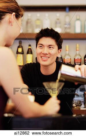 Man holding cocktail mixer, pouring drink for woman in front of him View Large Photo Image Stock Image - Man holding cocktail mixer, pouring drink for woman in front of him. Fotosearch
