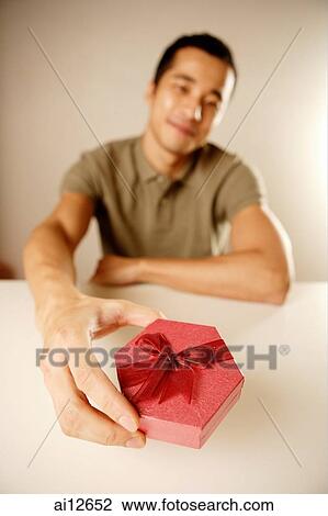 Stock Image - Man holding gift box. Fotosearch