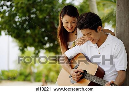 Man holding guitar, woman leaning on his shoulder View Large Photo Image Stock Image - Man holding guitar, woman leaning on his shoulder. Fotosearch