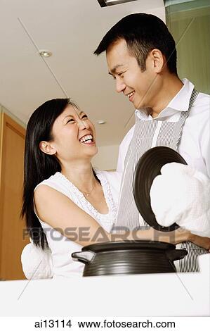 Picture - Man holding lid of pot, wife next to him, smiling. Fotosearch