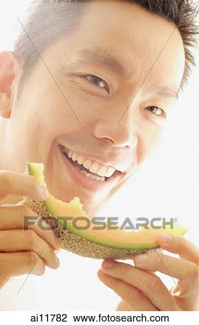 Man holding melon slice, smiling View Large Photo Image Stock Image - Man holding melon slice, smiling. Fotosearch