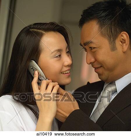 Man holding mobile phone to woman's ear. View Large Photo Image Stock Photo - Man holding mobile phone to woman's ear.. Fotosearch